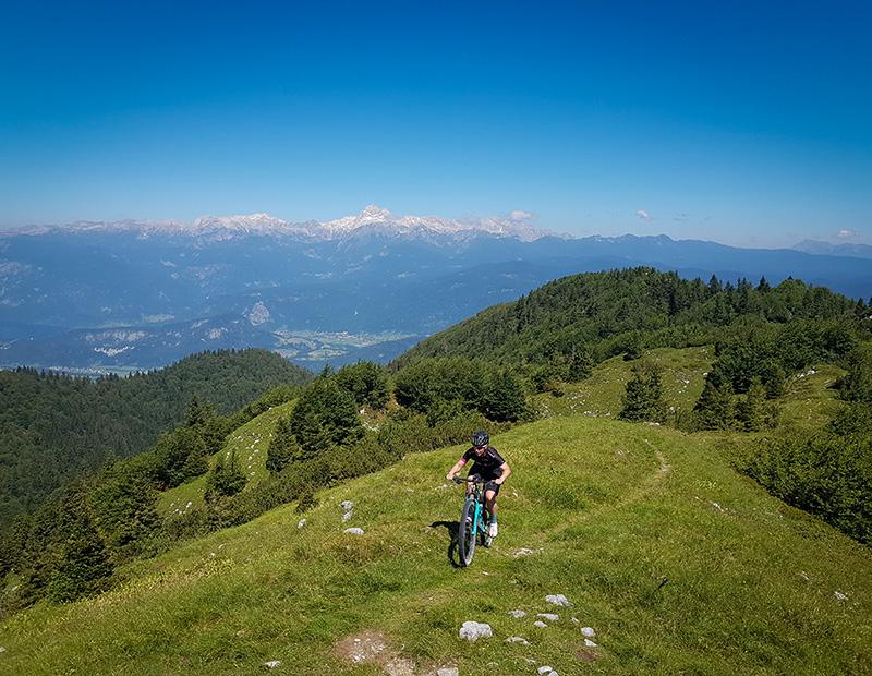 Mountain biker on a panoramic alpine ridge overlooking the Julian Alps and Mount Triglav